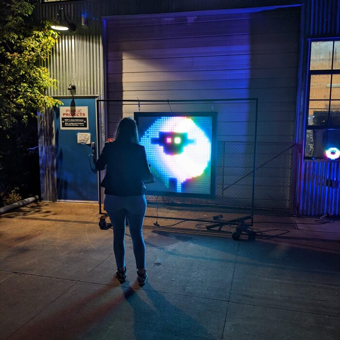 Pixel-lamb with woman in front of it